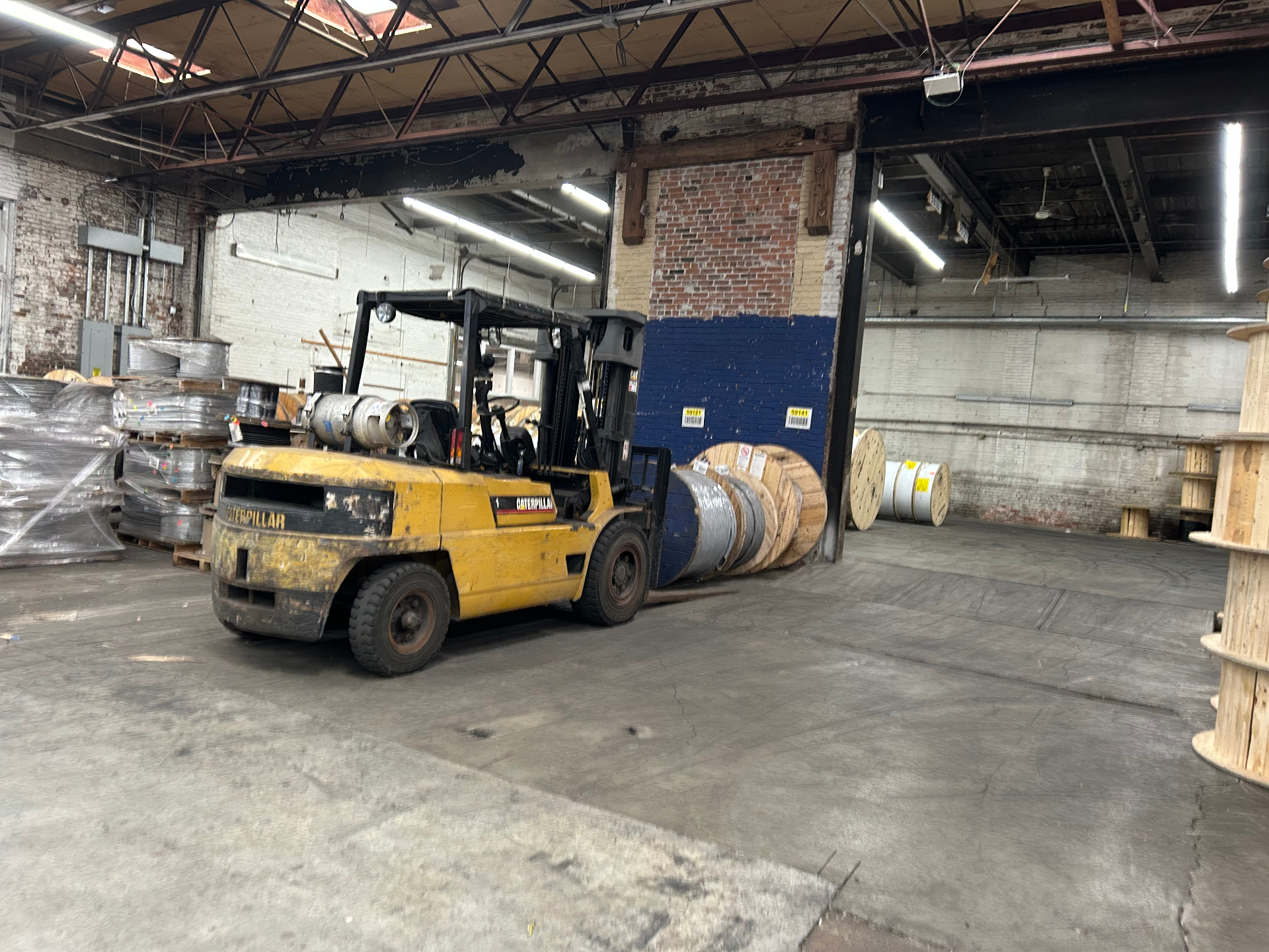 Caterpillar forklift moving wire spools inside a manufacturing warehouse